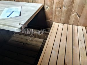 TimberIN Nordic Oval™ Terrace – interior: mesita abatible de pared en madera clara junto al banco de listones