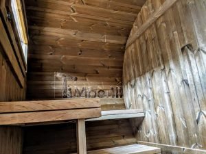 TimberIN Nordic Oval™ Terrace – interior: bancos de madera en dos niveles bajo una pequeña ventana, paredes curvas revestidas de madera