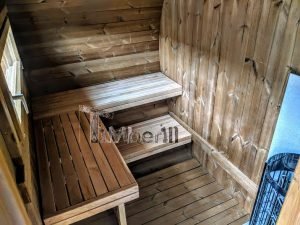 TimberIN Nordic Oval™ Terrace – interior: bancos de madera en dos niveles bajo una pequeña ventana, paredes curvas revestidas de madera