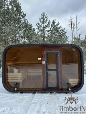 Sauna de jardín TimberIN Nordic Horizon con ventanal panorámico, vista frontal en un bosque nevado