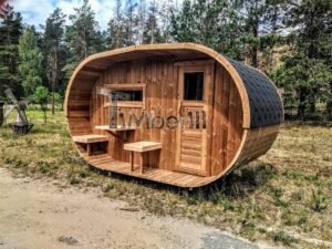 TimberIN Nordic Oval™ Terrace – sauna de exterior, vista de tres cuartos: cubierta de tejas negras, fachada de madera termotratada y porche cubierto con asientos abatibles y mesita