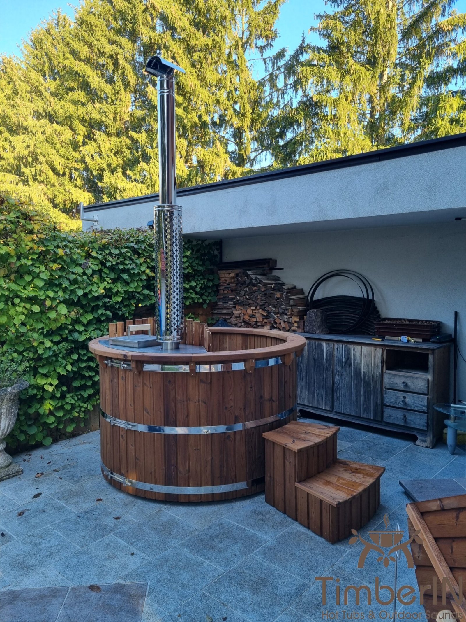 Jacuzzi redondo de madera termotratada marrón con escalera en una terraza