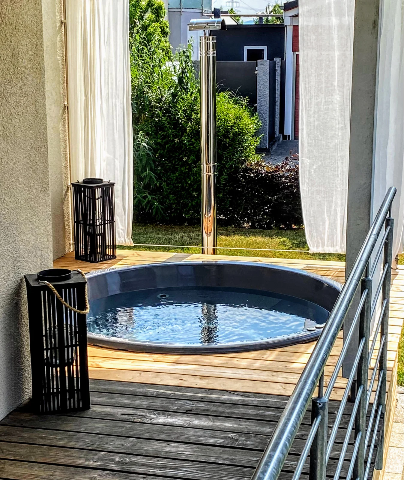 Jacuzzi en la terraza o el ático: peso, carga y permisos de la comunidad 1 Jacuzzi redondo integrado en una terraza de madera entre dos paredes de la casa