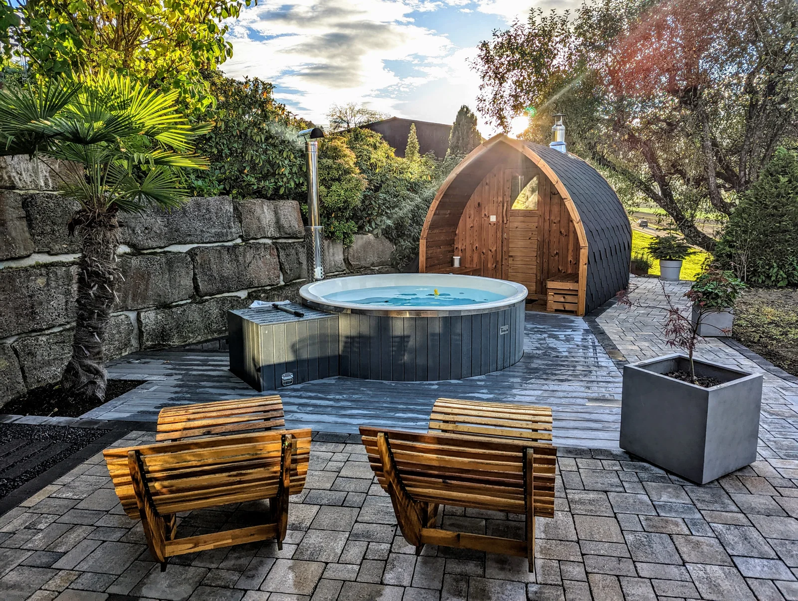 Terraza de jardín con jacuzzi abierto, tumbonas y sauna de exterior