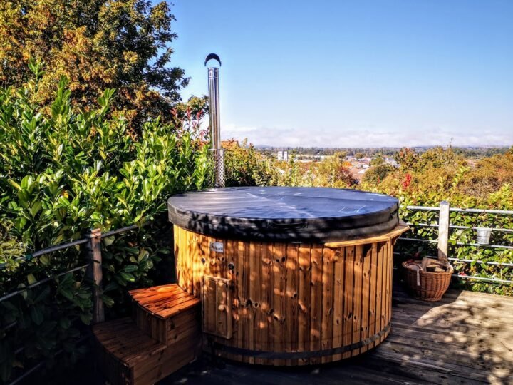 Jacuzzi de madera con chimenea y cubierta térmica sobre una terraza del jardín