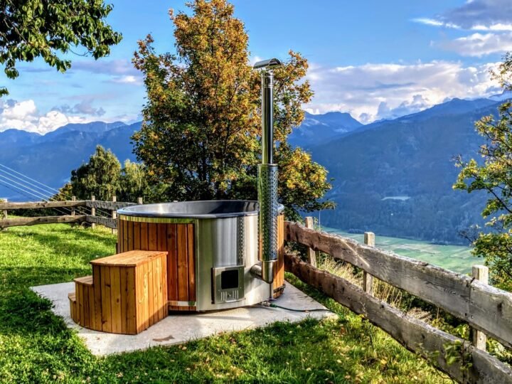 Jacuzzi con estufa de leña sobre el césped con vistas a las montañas