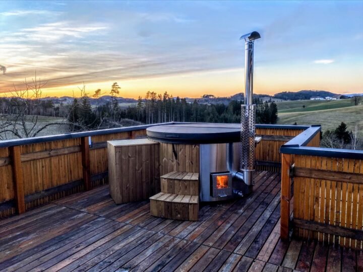 Jacuzzi sobre una terraza de madera con la estufa de leña encendida al atardecer