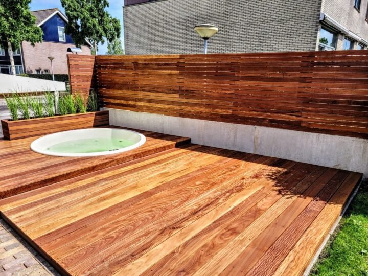Jacuzzi redondo con cubeta clara empotrado a ras en una terraza de madera con jardineras