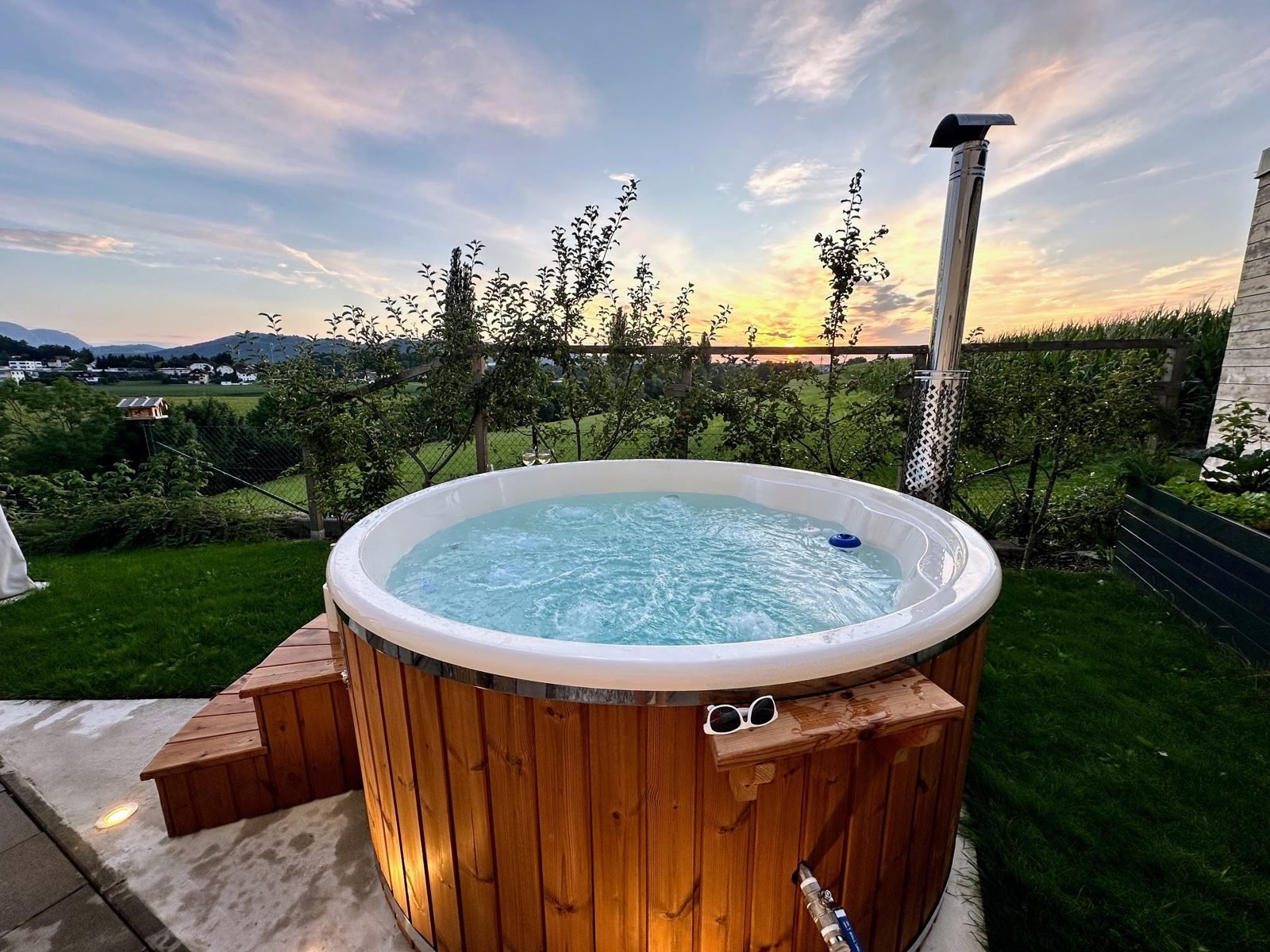 Jacuzzi de fibra de vidrio 1 Jacuzzi exterior de madera con agua burbujeante al atardecer en un jardín