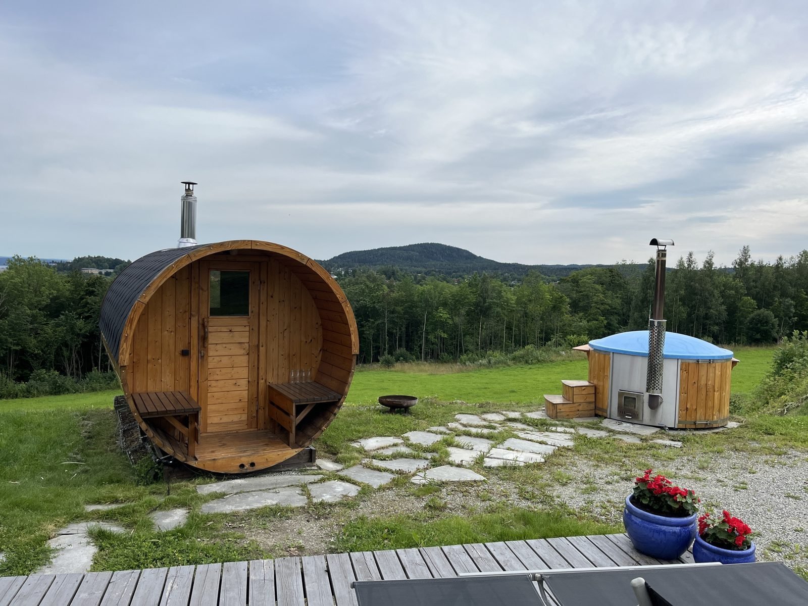 Sauna barril 1 Sauna de barril de madera con estufa de leña y chimenea en un jardín con vistas al campo