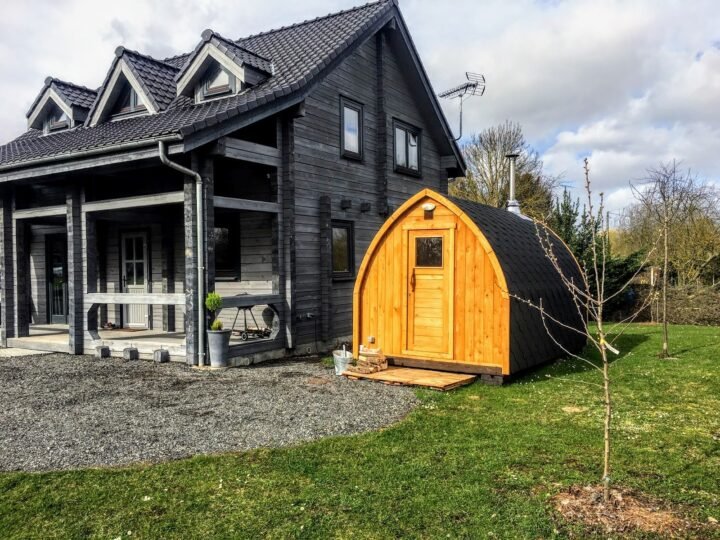 Sauna iglú de madera en el jardín junto a una casa
