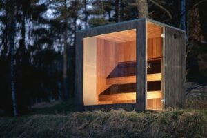Sauna de exterior TimberIN Nordic Cube de CLT con el acristalamiento iluminado