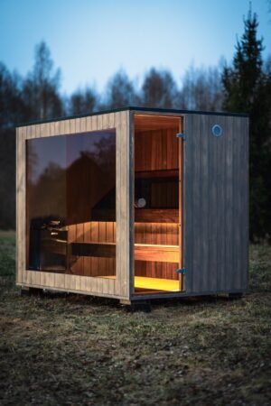 Sauna de exterior TimberIN Nordic Cube de CLT con frontal de cristal al atardecer