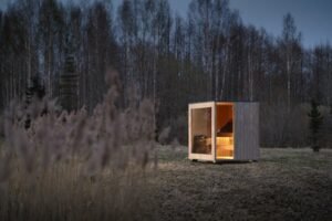 Sauna de exterior TimberIN Nordic Cube de CLT al anochecer en el bosque